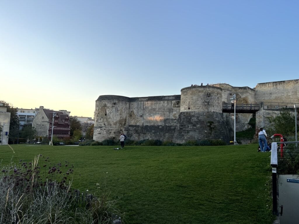 Château de Caen 11 The barbican of the Porte Saint-Pierre at the Château de Caen at dusk, two round drums on a battered plinth with a timber bridge running to the gate behind.