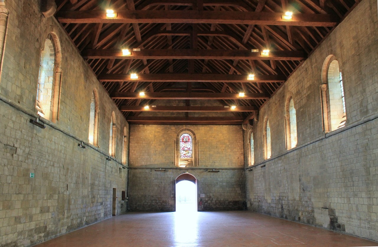 The interior of the Salle de l'Échiquier at the Château de Caen, a single undivided hall with round-arched windows in two registers and an open timber roof above. The interior of the Salle de l'Échiquier at the Château de Caen, a single undivided hall with round-arched windows in two registers and an open timber roof above.