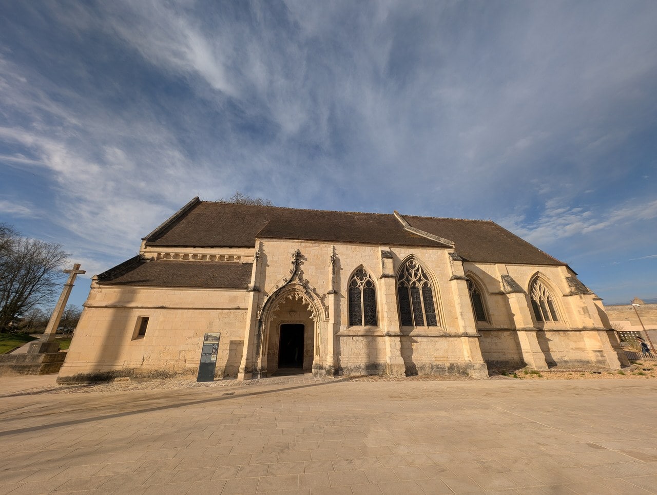 The exterior of the church of Saint-Georges inside the Château de Caen, showing its carved flamboyant porch, traceried windows and tiled roof, with a stone cross to the left. The exterior of the church of Saint-Georges inside the Château de Caen, showing its carved flamboyant porch, traceried windows and tiled roof, with a stone cross to the left.