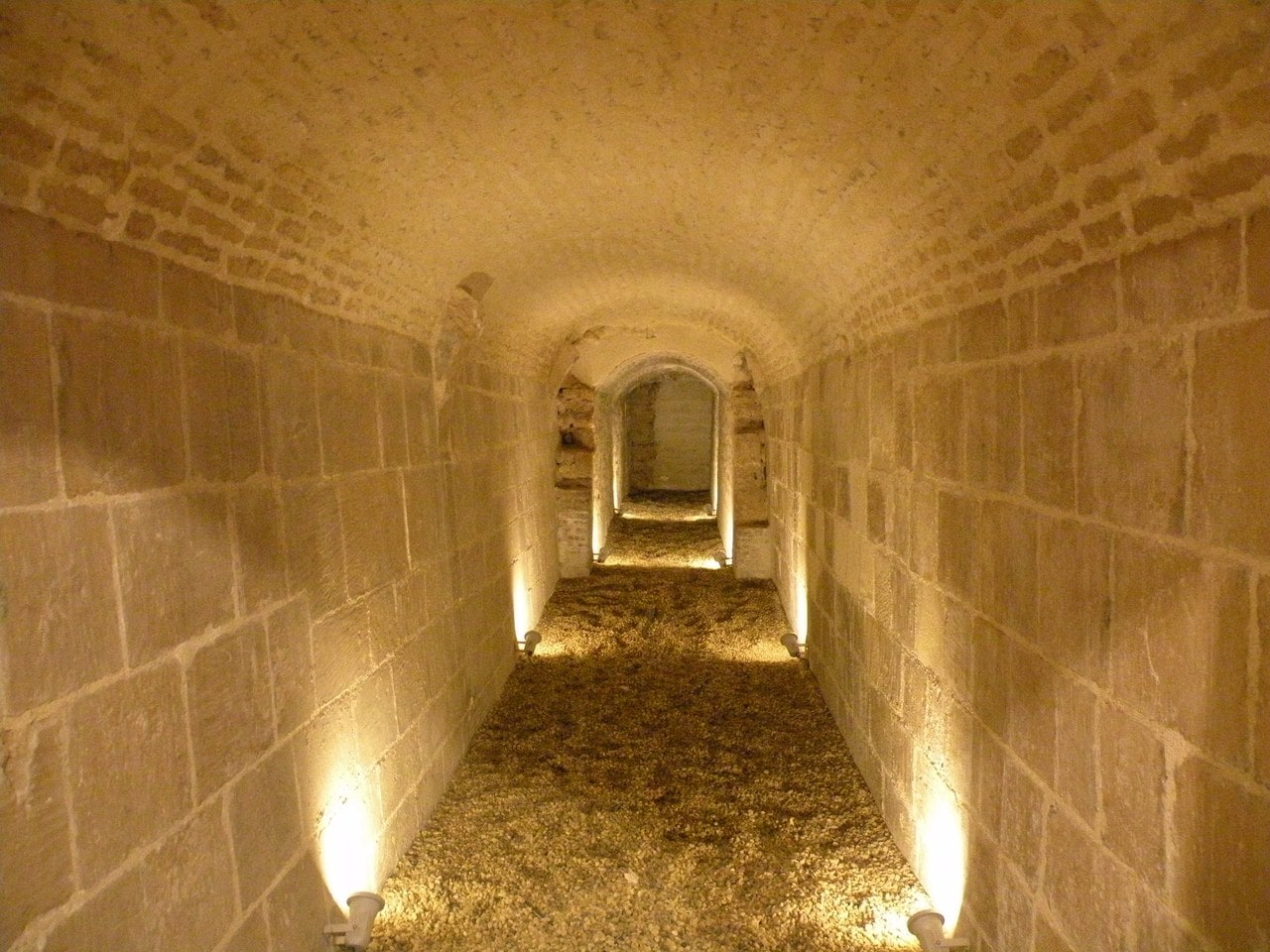 A barrel-vaulted ashlar passage running underground at the Château de Caen, lit along the base of its walls, with a smaller arch at the far end. A barrel-vaulted ashlar passage running underground at the Château de Caen, lit along the base of its walls, with a smaller arch at the far end.