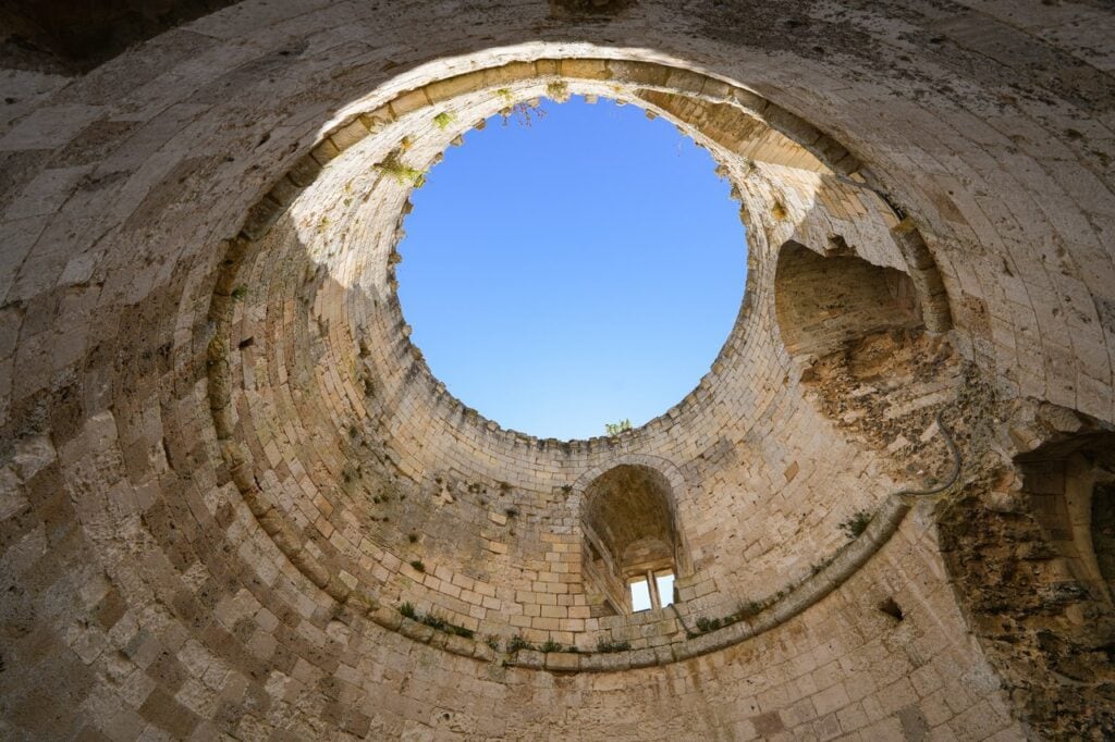 Château Gaillard 4 The interior of Château Gaillard's donjon, looking straight up the roofless circular tower to the sky, coursed stone all around and a window recess in the far wall.