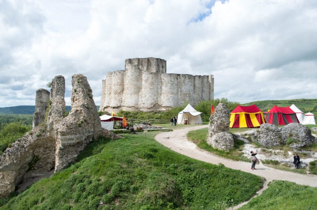 Château Gaillard 13 Striped red and yellow and plain white tents pitched on the grass below Château Gaillard's inner curtain, with visitors walking the paths between the ruins.