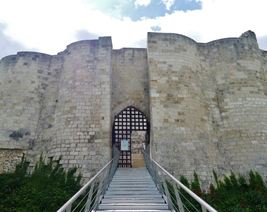 Château Gaillard 10 A modern steel staircase rising between two segments of Château Gaillard's curtain wall to a pointed-arched gateway closed with a portcullis-like grille.