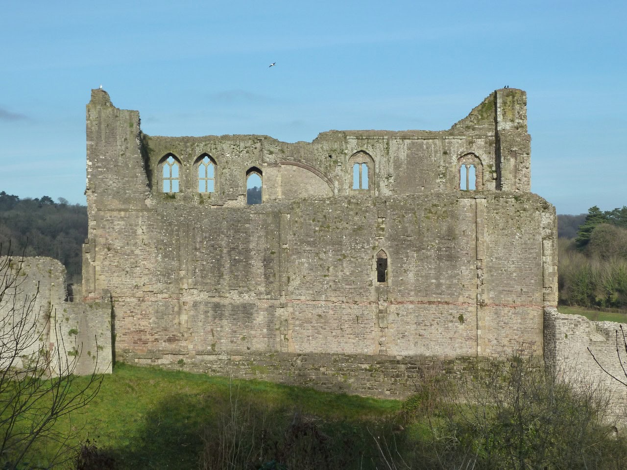 The long elevation of the Great Tower at Chepstow Castle, a roofless rectangular block, with a thin band of red tile running horizontally right across the wall and paler masonry pierced by tall two-light windows standing above the band. The long elevation of the Great Tower at Chepstow Castle, a roofless rectangular block, with a thin band of red tile running horizontally right across the wall and paler masonry pierced by tall two-light windows standing above the band.
