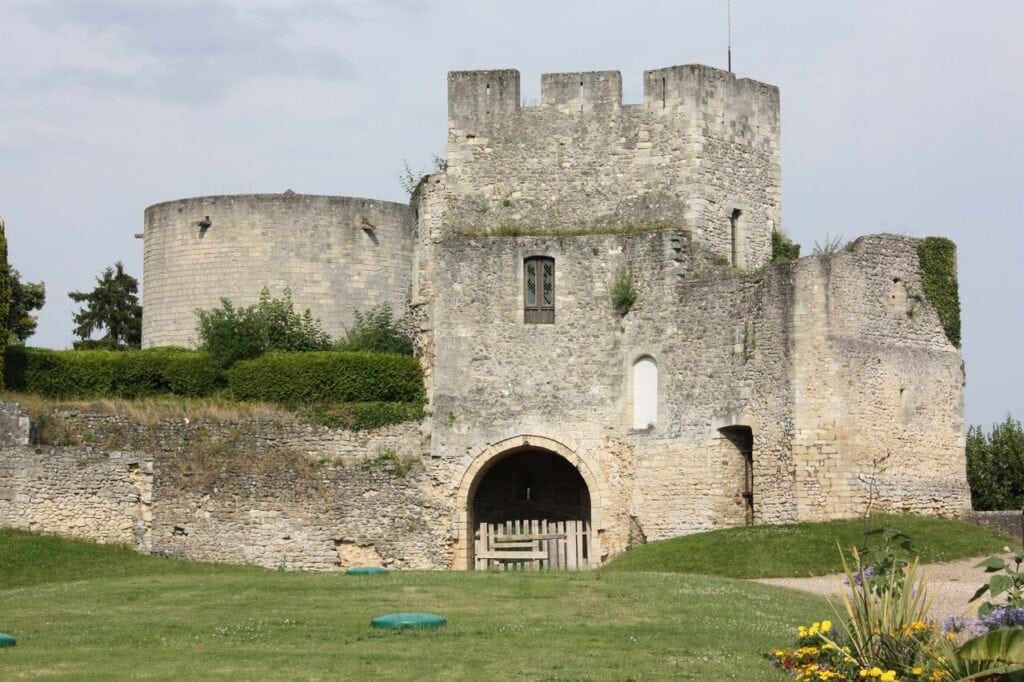 Château de Gisors 6 The crenellated gatehouse of Chateau de Gisors above an arched gateway, with a smooth ashlar cylindrical tower rising behind it to the left.