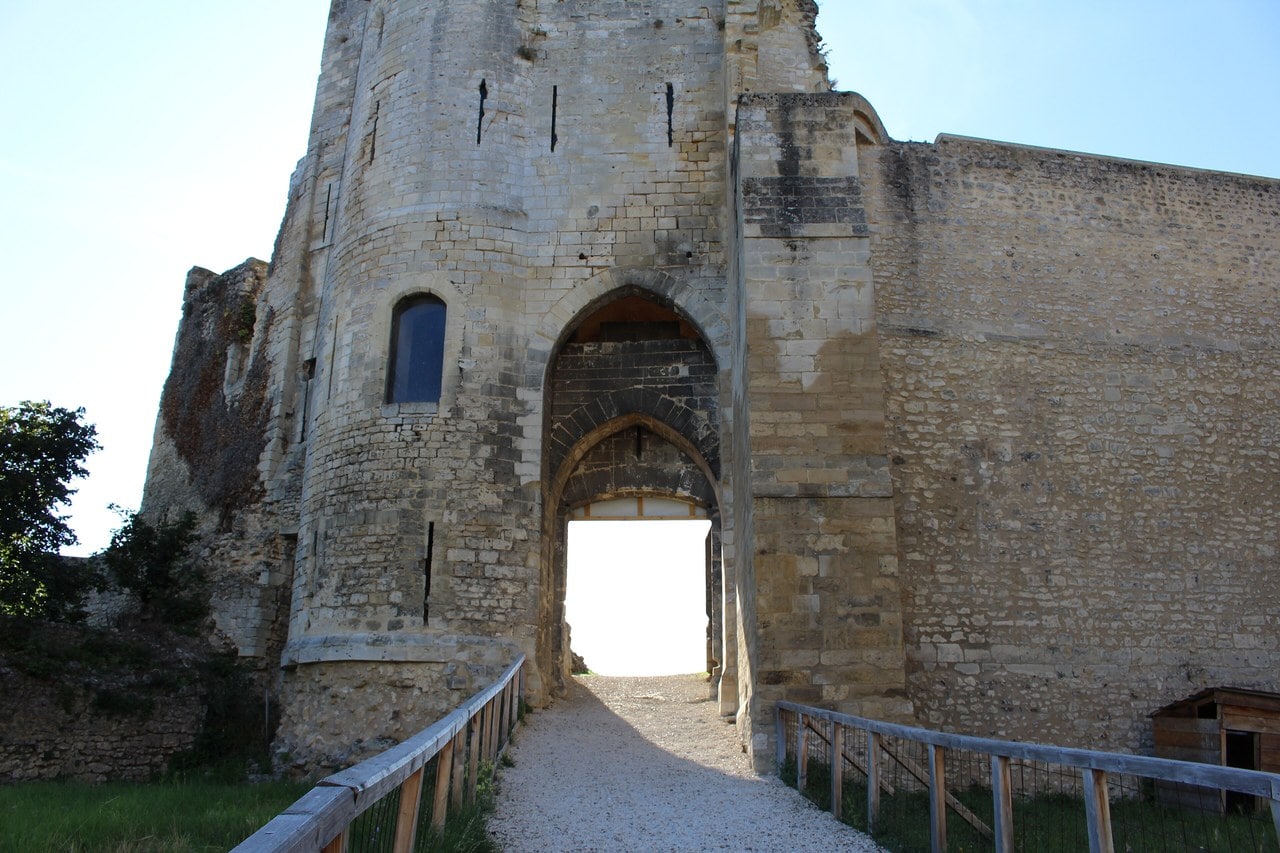 A gravel causeway with wooden handrails leading into the two-order pointed archway of the gatehouse at Chateau de Gisors, a rounded turret with arrow slits on the left. A gravel causeway with wooden handrails leading into the two-order pointed archway of the gatehouse at Chateau de Gisors, a rounded turret with arrow slits on the left.
