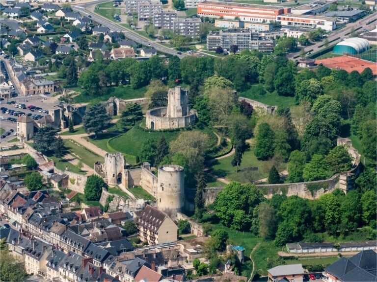 Home 10 An oblique aerial view of Chateau de Gisors, the motte and its keep at the centre of a walled enclosure of parkland, with the town pressing against the walls on one side.