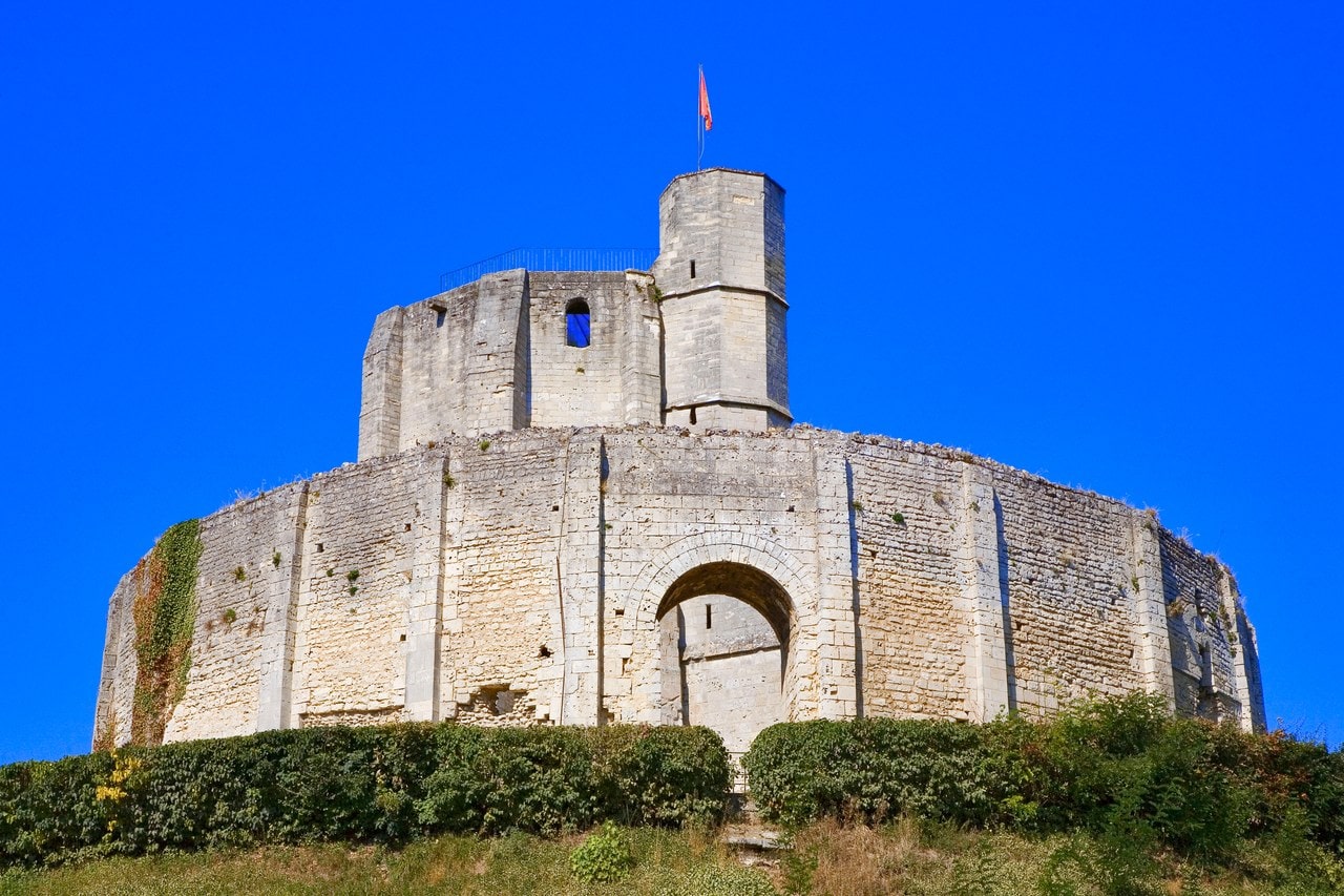 The octagonal great tower of Château de Gisors rising inside a tall buttressed chemise on top of its motte, a polygonal stair turret with a flag at the summit. The octagonal great tower of Château de Gisors rising inside a tall buttressed chemise on top of its motte, a polygonal stair turret with a flag at the summit.