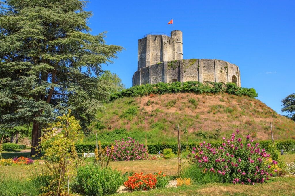 Château de Gisors 2 The turf motte of Chateau de Gisors topped by its ring wall and keep, a cedar at the left and rose beds across the foreground.