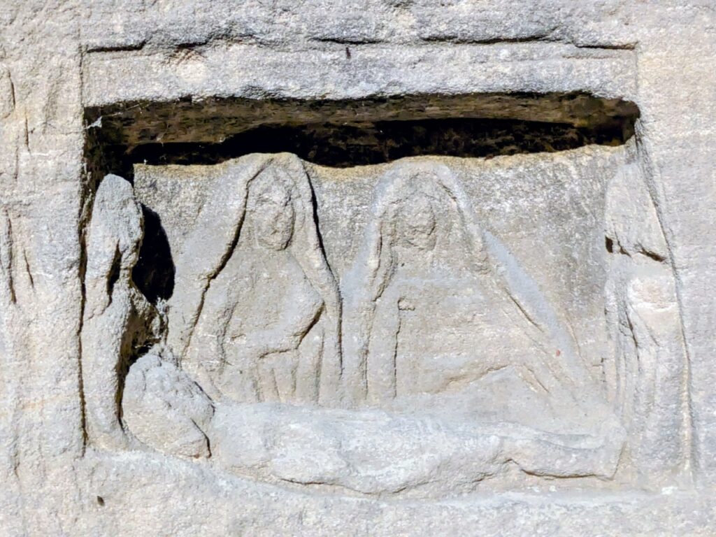Château de Gisors 12 A relief carving of a body laid on a slab with draped standing figures behind it, cut into a wall block in the Prisoner's Tower at Chateau de Gisors.