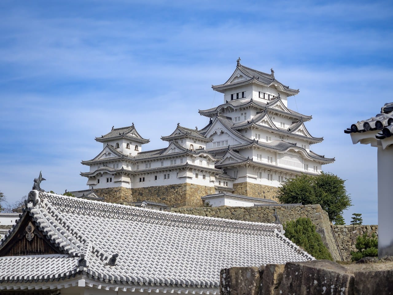 The keep group of Himeji Castle: a tall white keep of several roofed stages at the right on a stone base, with two lower towers beside it to the left, connected to it and to each other by roofed linking ranges. The keep group of Himeji Castle: a tall white keep of several roofed stages at the right on a stone base, with two lower towers beside it to the left, connected to it and to each other by roofed linking ranges.