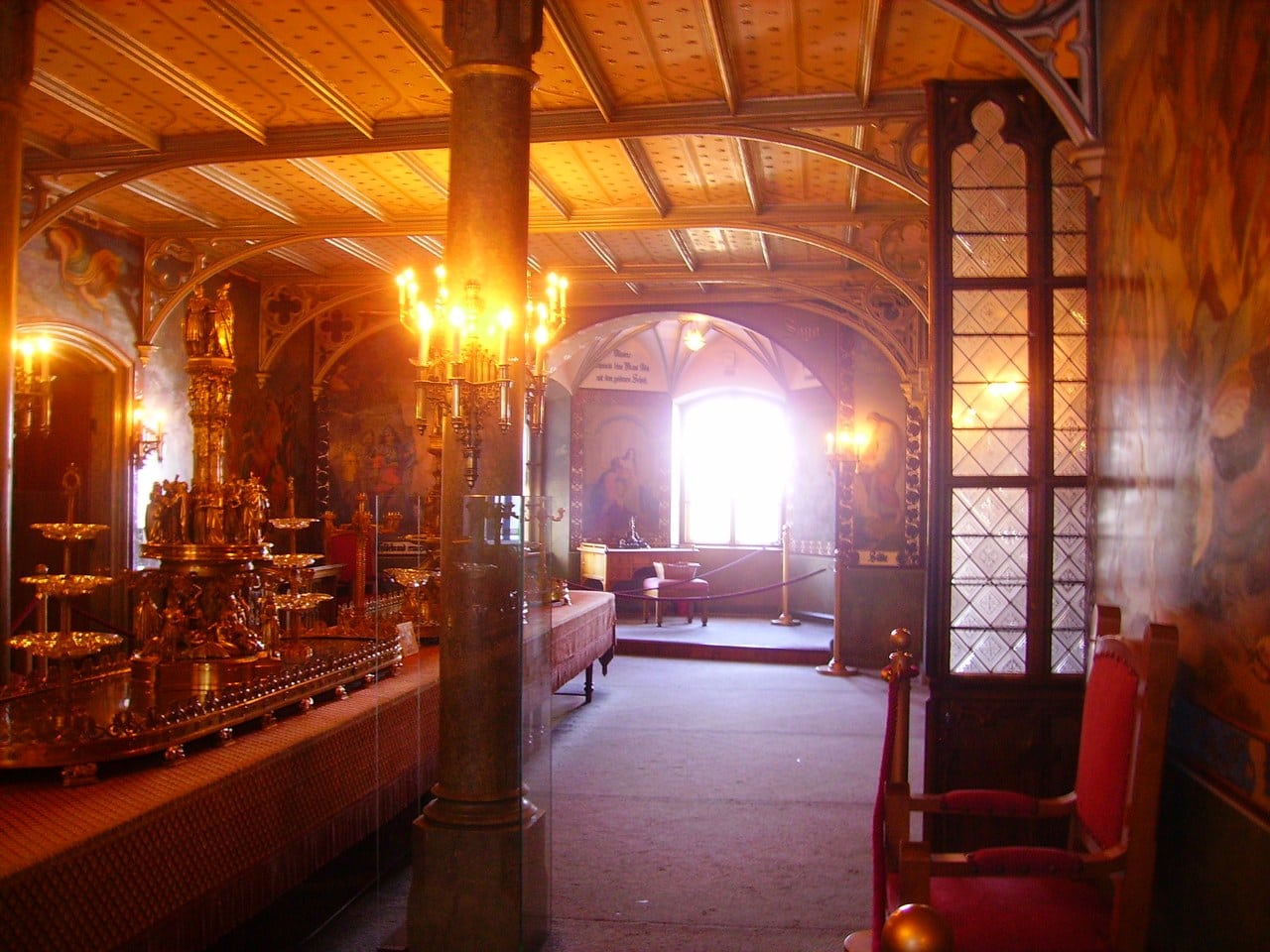 The great festival hall of Hohenschwangau Castle, its flat timber ceiling carried on a heavy column, wall paintings along both sides and a long table set with gilt plate The great festival hall of Hohenschwangau Castle, its flat timber ceiling carried on a heavy column, wall paintings along both sides and a long table set with gilt plate