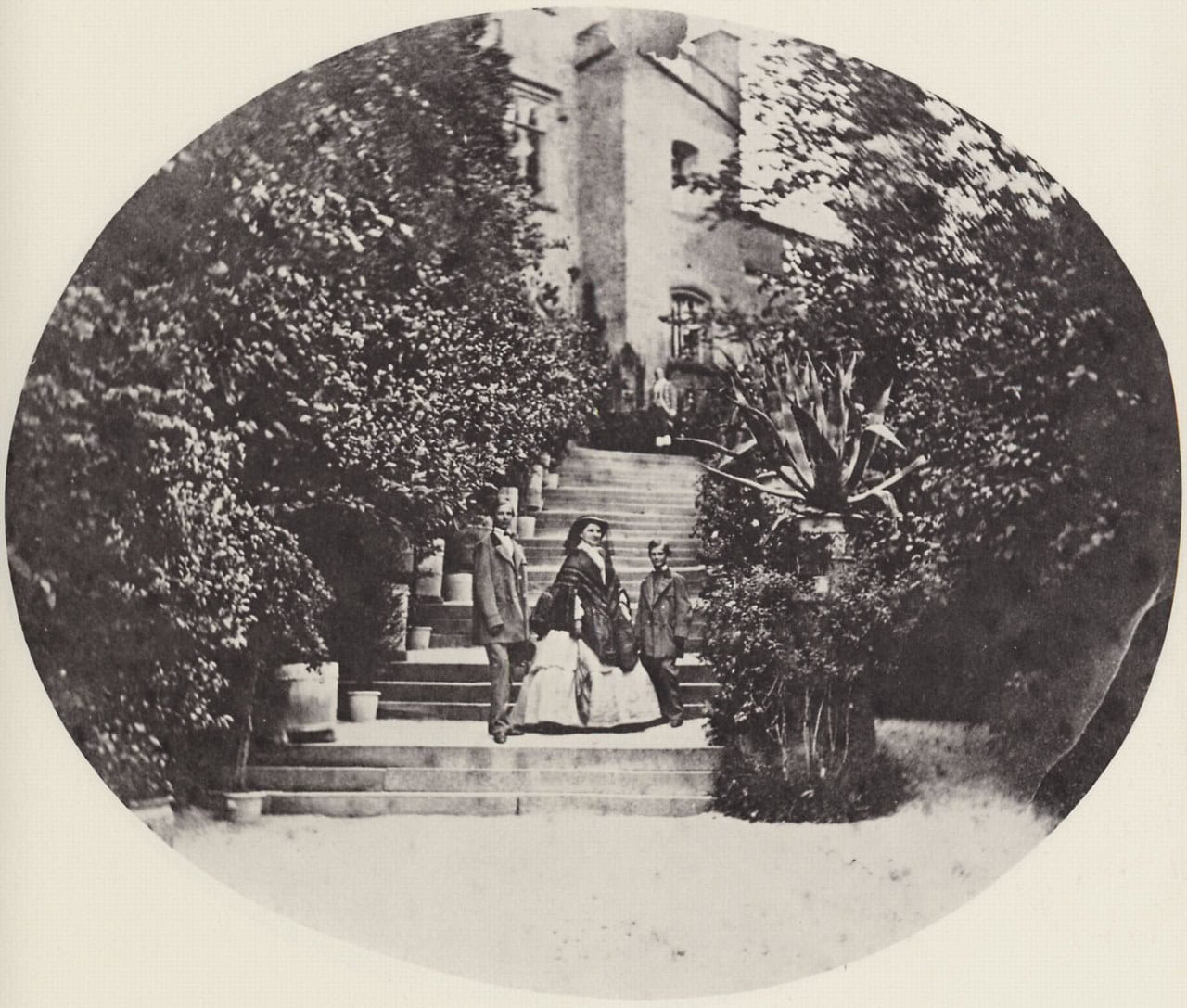 An early oval photograph of the castle staircase at Hohenschwangau, with several figures standing on the steps among shrubs and potted plants An early oval photograph of the castle staircase at Hohenschwangau, with several figures standing on the steps among shrubs and potted plants