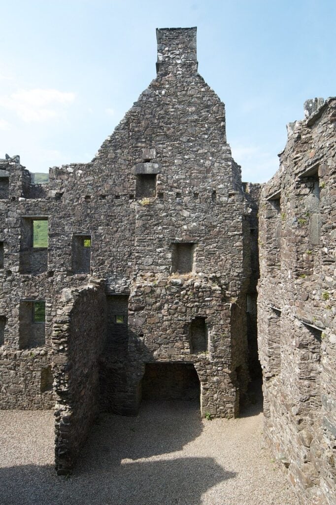 Kilchurn Castle 5 A tall gabled range inside Kilchurn Castle's courtyard, a chimney stack rising at the apex above two levels of window openings, with a low passage at ground level.