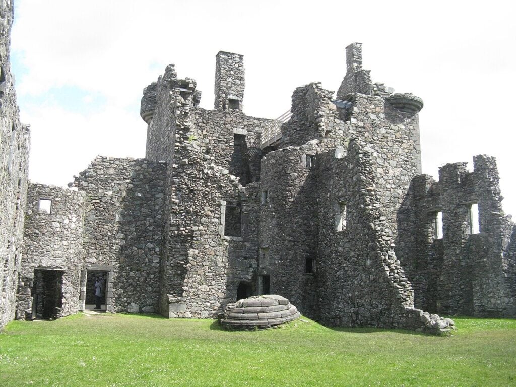 Kilchurn Castle 4 The courtyard front of Kilchurn Castle's tower house, with corbelled round turrets at the wall head and the fallen stone turret lying on the grass below.