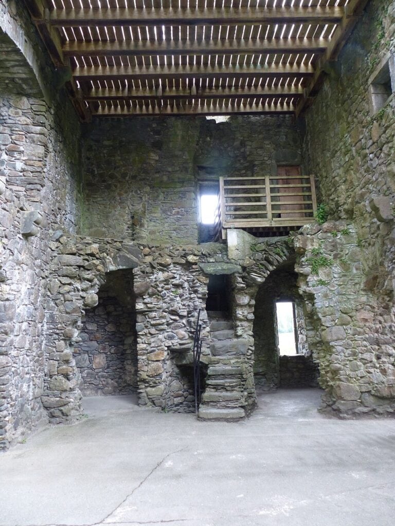 Kilchurn Castle 8 A ground-floor chamber inside Kilchurn Castle with a poured concrete floor, a modern timber deck spanning overhead and a stone stair rising within the wall thickness.