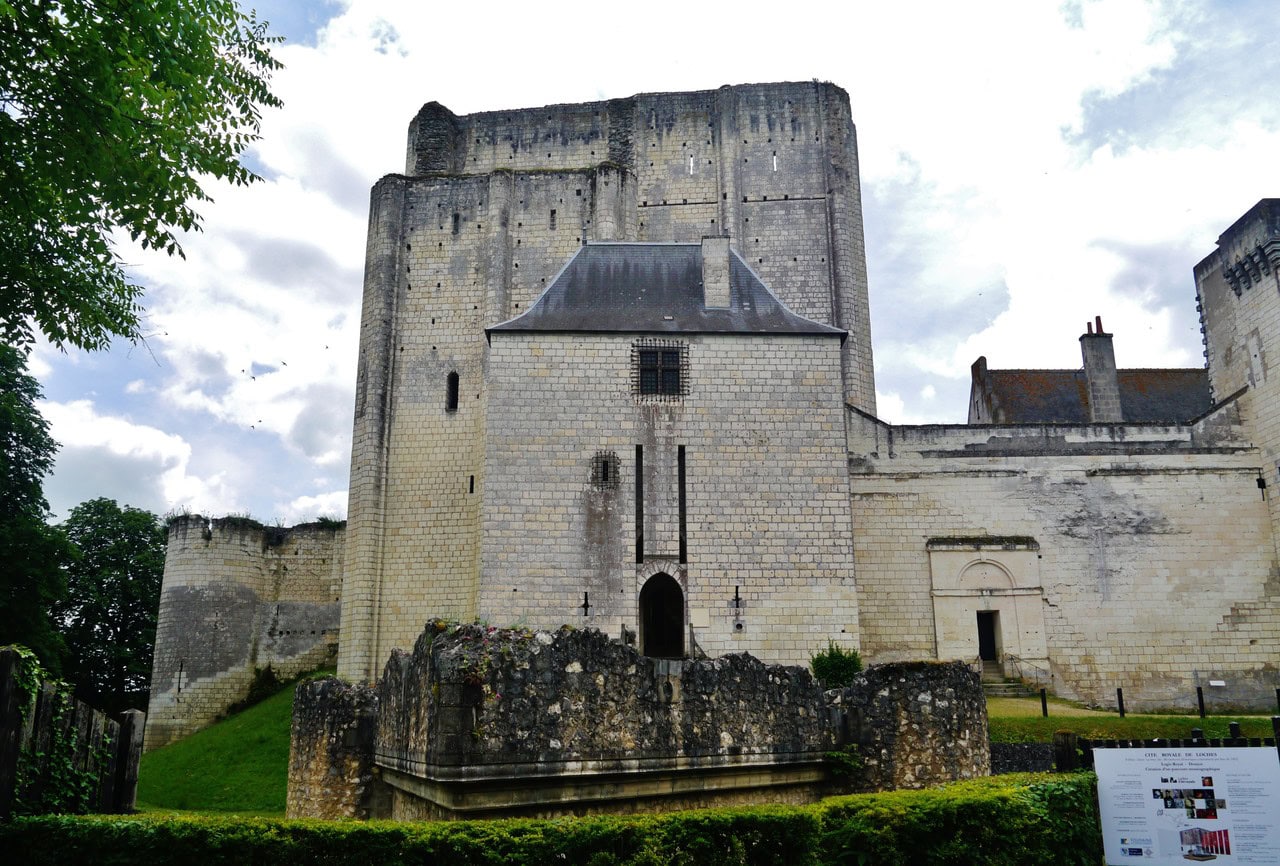 The rectangular great tower of Loches with its top missing, seen from the north, with the smaller roofed petit-donjon standing against its face and an arched doorway at the forebuilding's base.