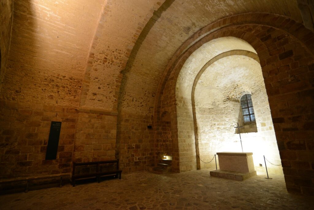 Mont-Saint-Michel 19 A Romanesque crypt under a wide plain barrel vault, with a small altar against the far wall