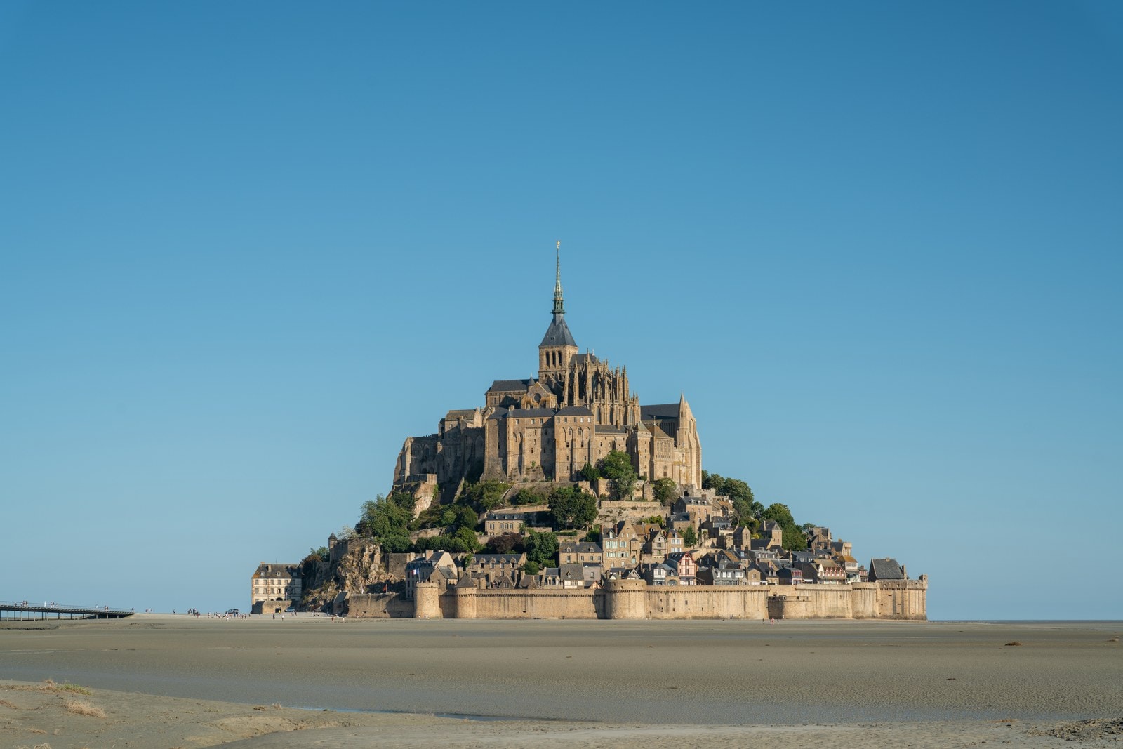 Mont-Saint-Michel 1 Mont-Saint-Michel rising from wet sand flats at low tide, village roofs stacked below the abbey church and spire