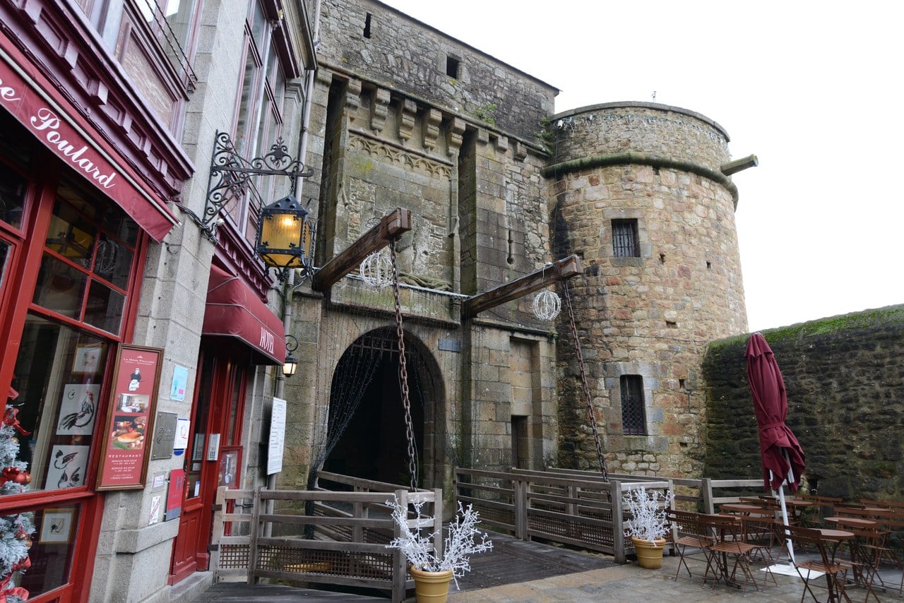 The stone gate passage of the porte du Roi with a round flanking tower, shopfronts to the left The stone gate passage of the porte du Roi with a round flanking tower, shopfronts to the left
