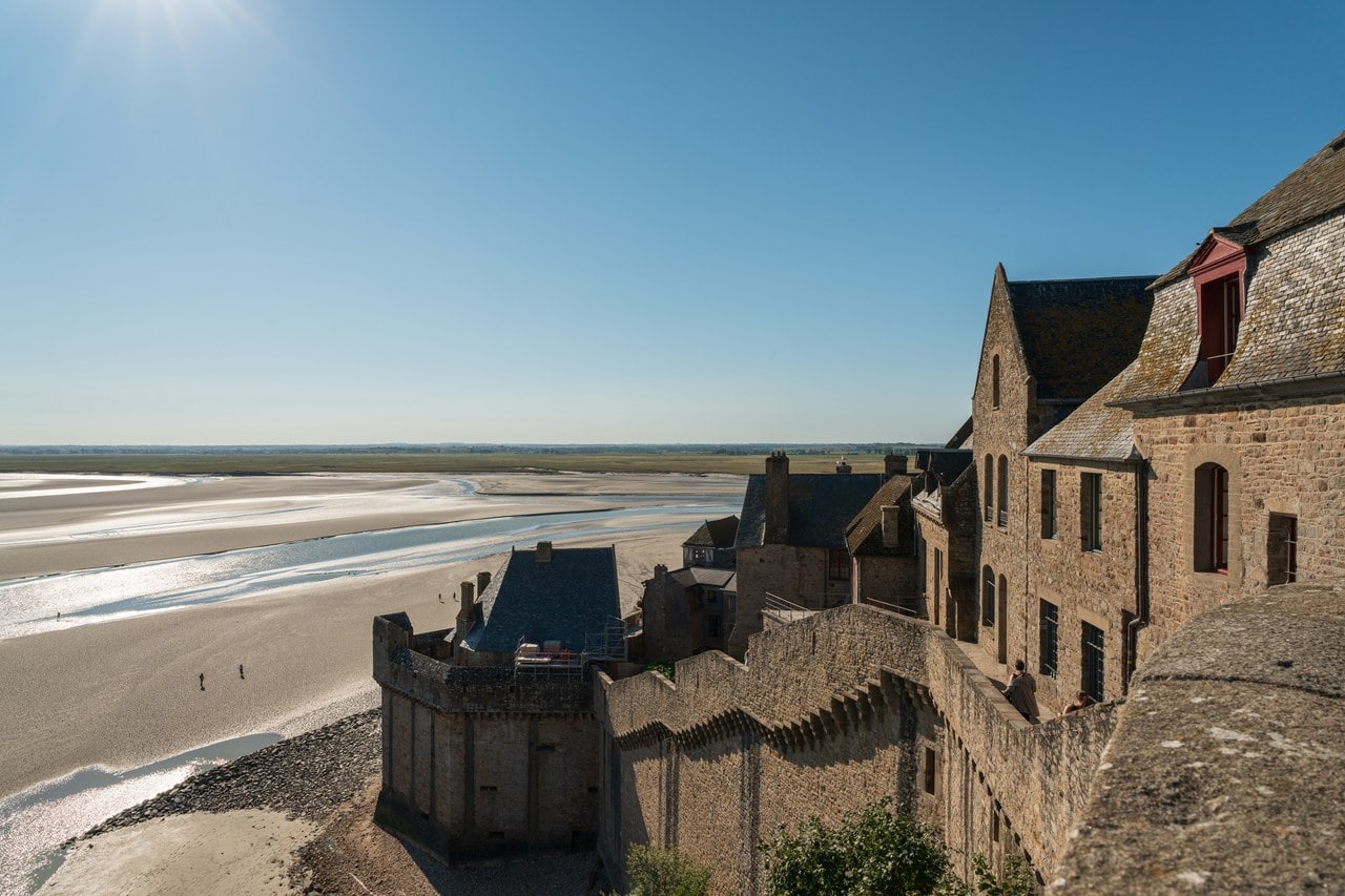 Stone curtain wall and a projecting stepped bastion below the village houses, with wet sand beyond Stone curtain wall and a projecting stepped bastion below the village houses, with wet sand beyond