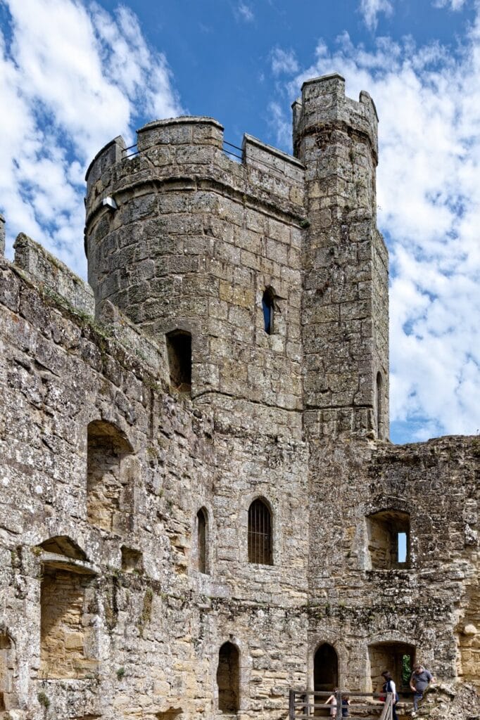 Round corner tower of Bodiam Castle rising above the curtain wall against a blue sky