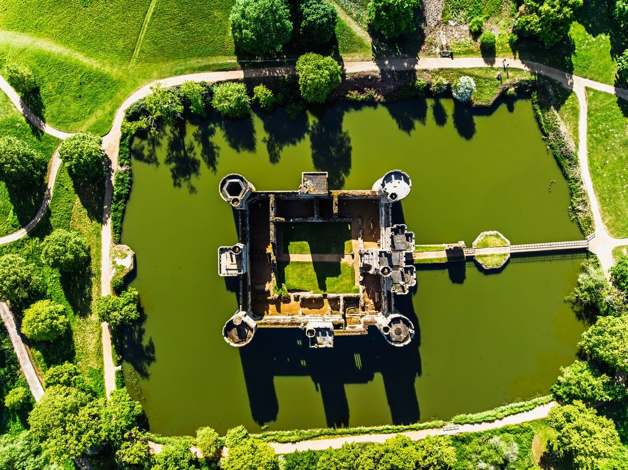 Overhead aerial of Bodiam Castle in its moat, north to the right, the straight modern bridge and causeway running from the north shore across the octagonal platform to the gatehouse