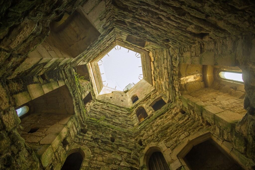 Interior of a roofless tower at Bodiam Castle looking up to a bright opening of sky