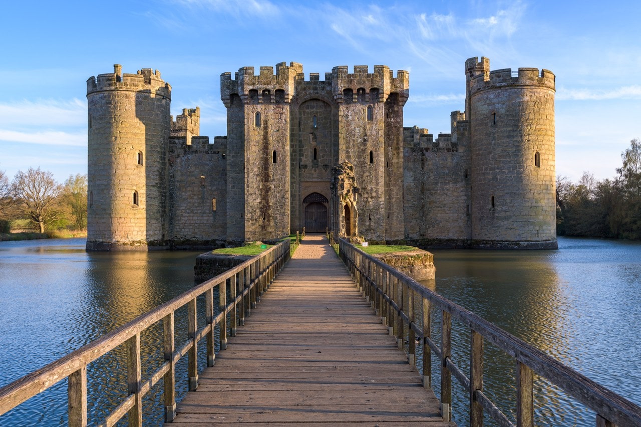 Wooden footbridge crossing the moat straight towards the twin-towered gatehouse of Bodiam Castle