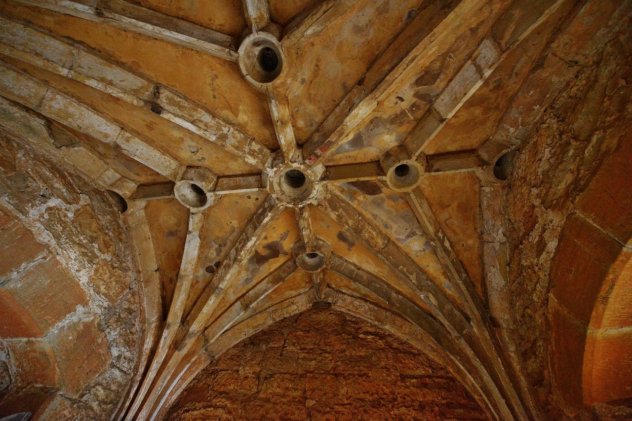 Ribbed stone vault above the gate passage at Bodiam Castle, round holes piercing the bosses where the ribs meet