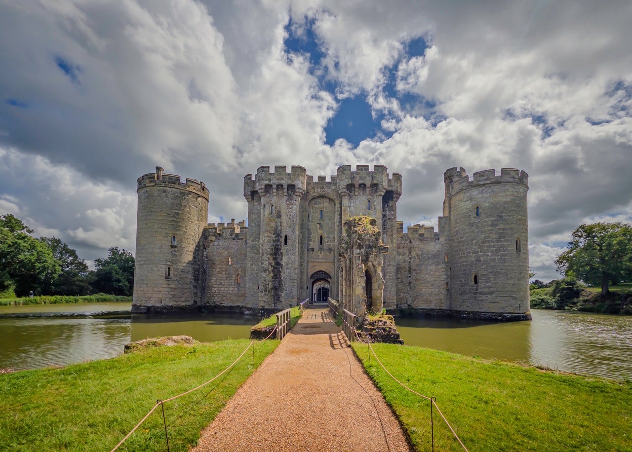 North front of Bodiam Castle at the end of a grass causeway under a heavy cloudy sky