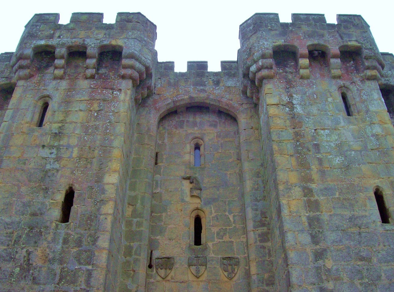 Front of the twin-towered gatehouse at Bodiam Castle with three carved shields set above the entrance arch