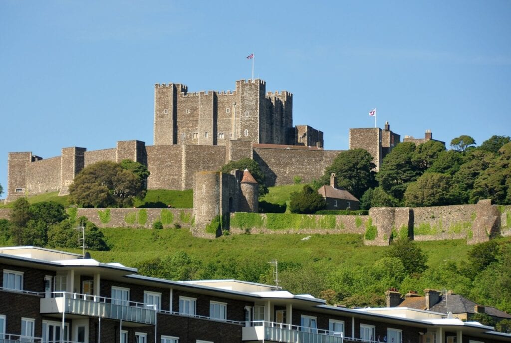 Dover Castle 3 Dover Castle strung along the top of a green chalk ridge above modern buildings on the seafront.