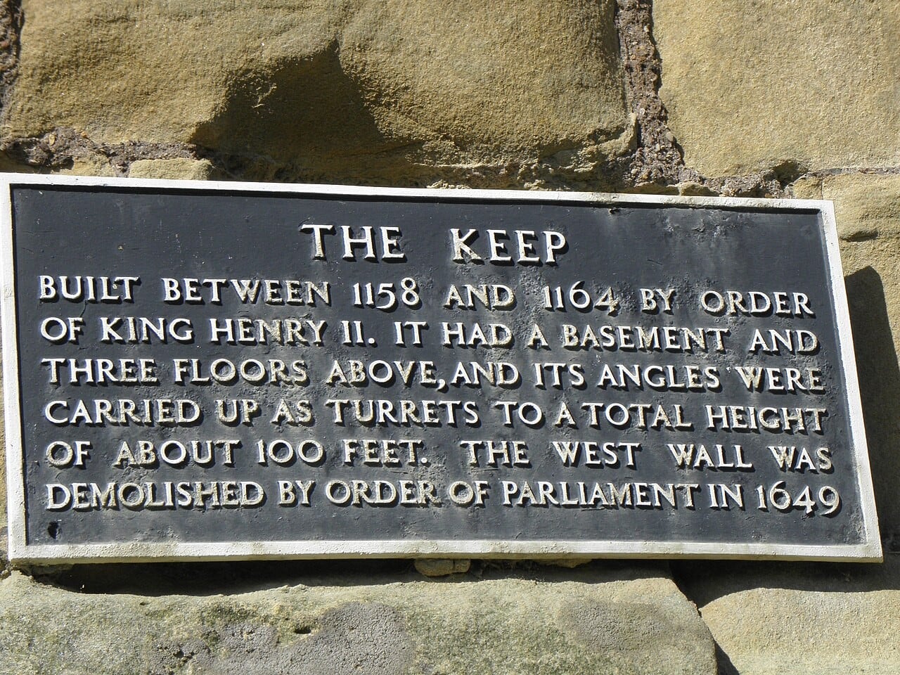 A dark metal plaque fixed to a sandstone wall, headed THE KEEP, reading that it was built between 1158 and 1164 by order of King Henry II, had a basement and three floors above with turrets to about 100 feet, and that the west wall was demolished by order of Parliament in 1649. A dark metal plaque fixed to a sandstone wall, headed THE KEEP, reading that it was built between 1158 and 1164 by order of King Henry II, had a basement and three floors above with turrets to about 100 feet, and that the west wall was demolished by order of Parliament in 1649.
