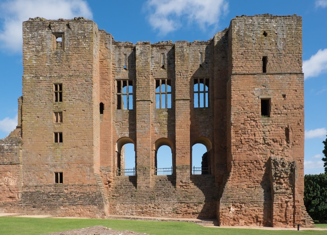 The flat face of the red sandstone Great Tower between two broad corner turrets, with three round-headed openings fitted with railings above a solid lower wall and three tall rectangular windows with stone mullions above them, under a blue sky. The flat face of the red sandstone Great Tower between two broad corner turrets, with three round-headed openings fitted with railings above a solid lower wall and three tall rectangular windows with stone mullions above them, under a blue sky.