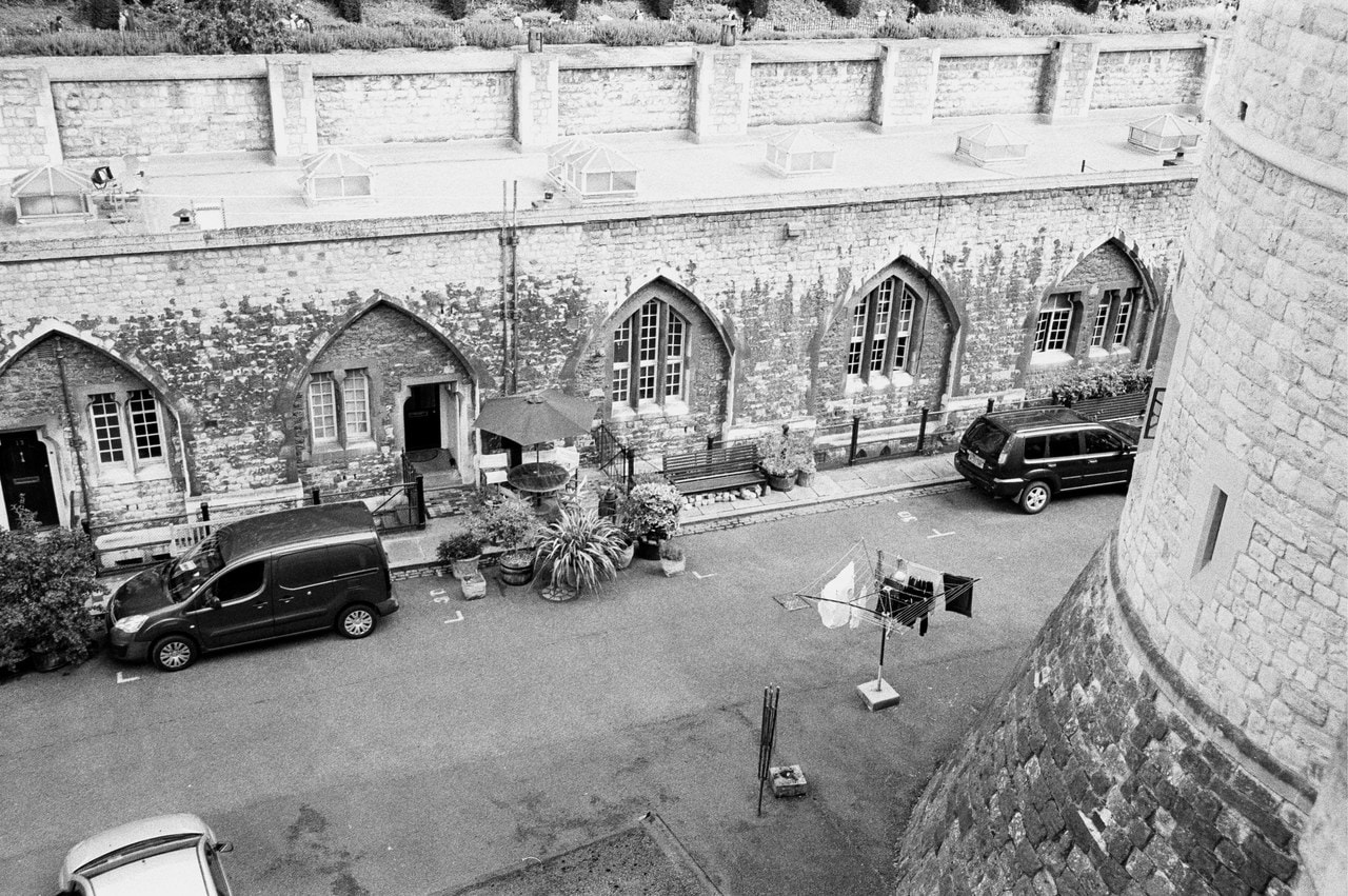 A black-and-white view from above of houses built into the old walls along Mint Street, with parked cars, pot plants and a rotary washing line.