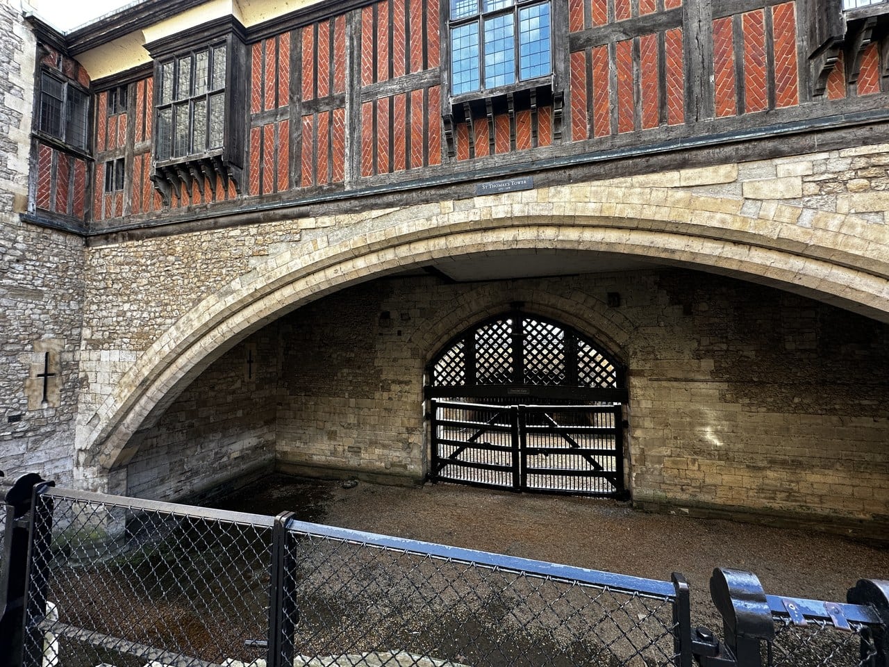 A broad stone arch closed at the back by a timber lattice gate, with the timber-framed upper story of St Thomas's Tower above it.