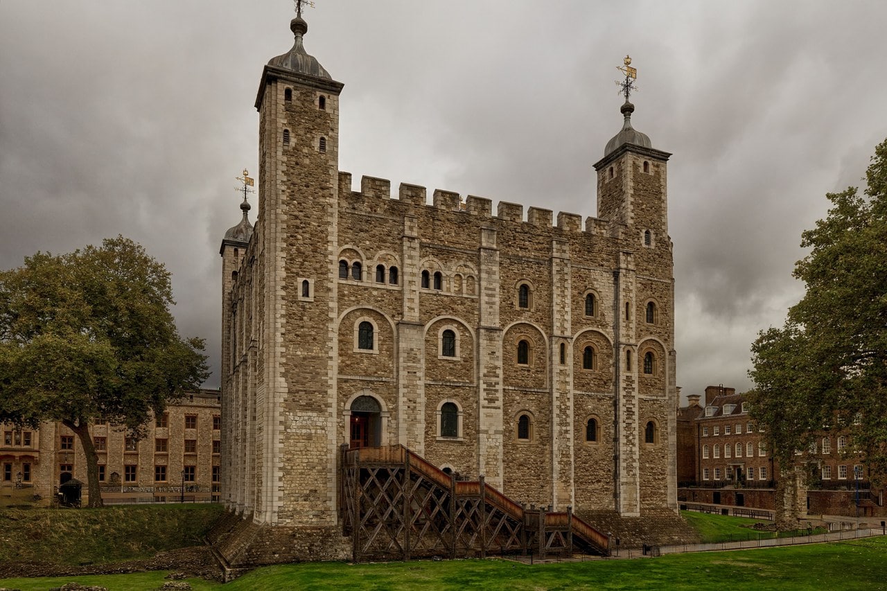 The White Tower seen across a lawn, a pale stone keep with corner turrets and cupolas, with a timber staircase climbing to its raised entrance.