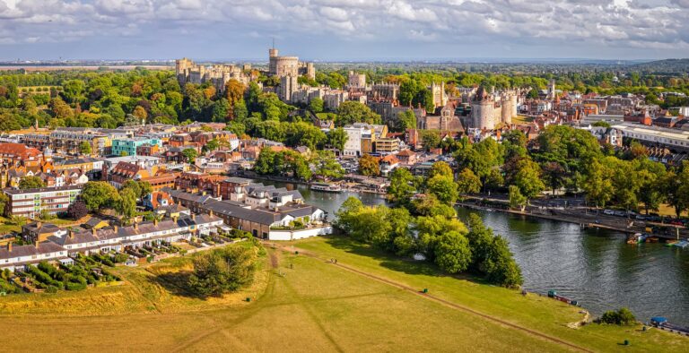 Home 9 Aerial view of Windsor Castle on a low ridge above the roofs of the town, with the River Thames curving through open meadow in the foreground