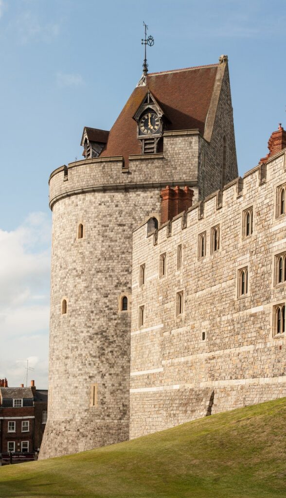 Windsor Castle 7 A massive drum tower of coursed stone with a steep tiled roof and a clock, rising at the western point of the castle wall