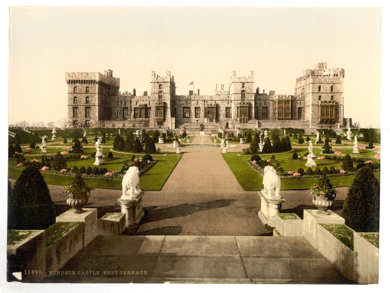 A color photochrom print of a formal terrace garden with clipped cones and statues, the battlemented east front of the castle behind A color photochrom print of a formal terrace garden with clipped cones and statues, the battlemented east front of the castle behind