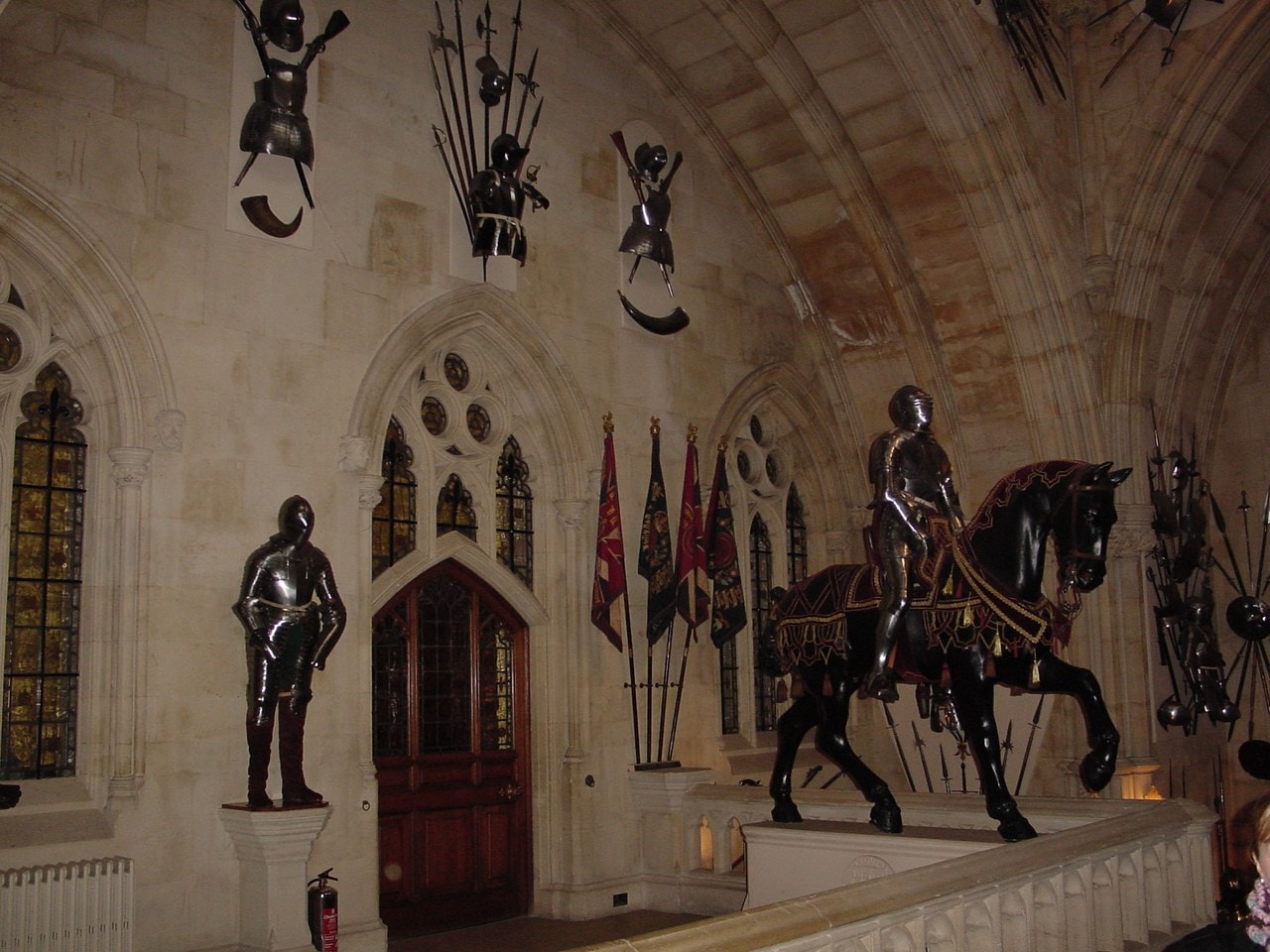 A vaulted Gothic hall with trophies of swords and pistols arranged on the walls, a suit of armor on a plinth and an armored figure on horseback A vaulted Gothic hall with trophies of swords and pistols arranged on the walls, a suit of armor on a plinth and an armored figure on horseback