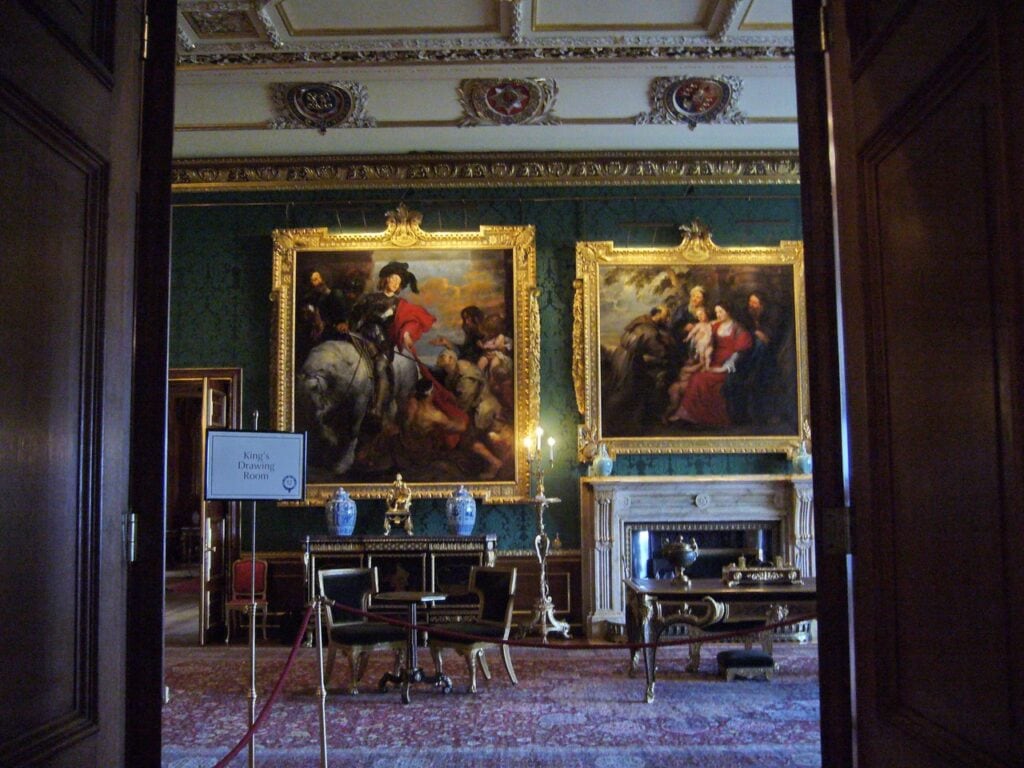 Windsor Castle 12 A green-walled state room with two large gilt-framed paintings and a white marble chimneypiece, below a white and gilt plaster ceiling set with heraldic cartouches