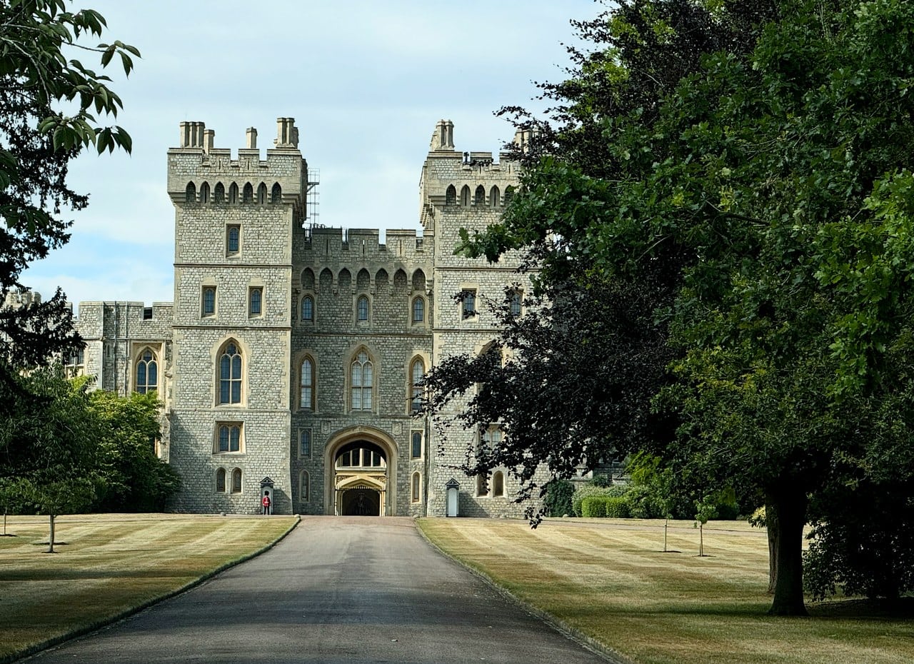 A straight tree-lined avenue leading to a twin-turreted stone gateway in the castle's south front, framed by the dark canopy of two trees A straight tree-lined avenue leading to a twin-turreted stone gateway in the castle's south front, framed by the dark canopy of two trees