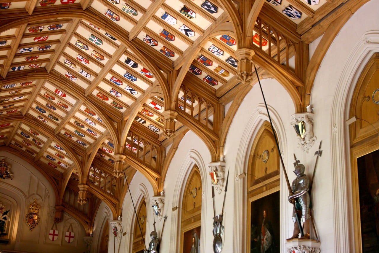 An open timber roof of pointed arches seen from below, the panels between the ribs filled with painted heraldic shields, above a wall hung with portraits and armor An open timber roof of pointed arches seen from below, the panels between the ribs filled with painted heraldic shields, above a wall hung with portraits and armor
