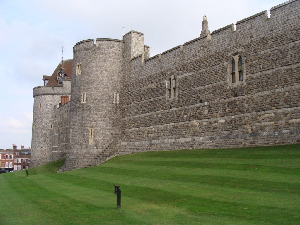 Windsor Castle 8 A long battlemented curtain wall with a projecting drum tower, falling away down a grass bank