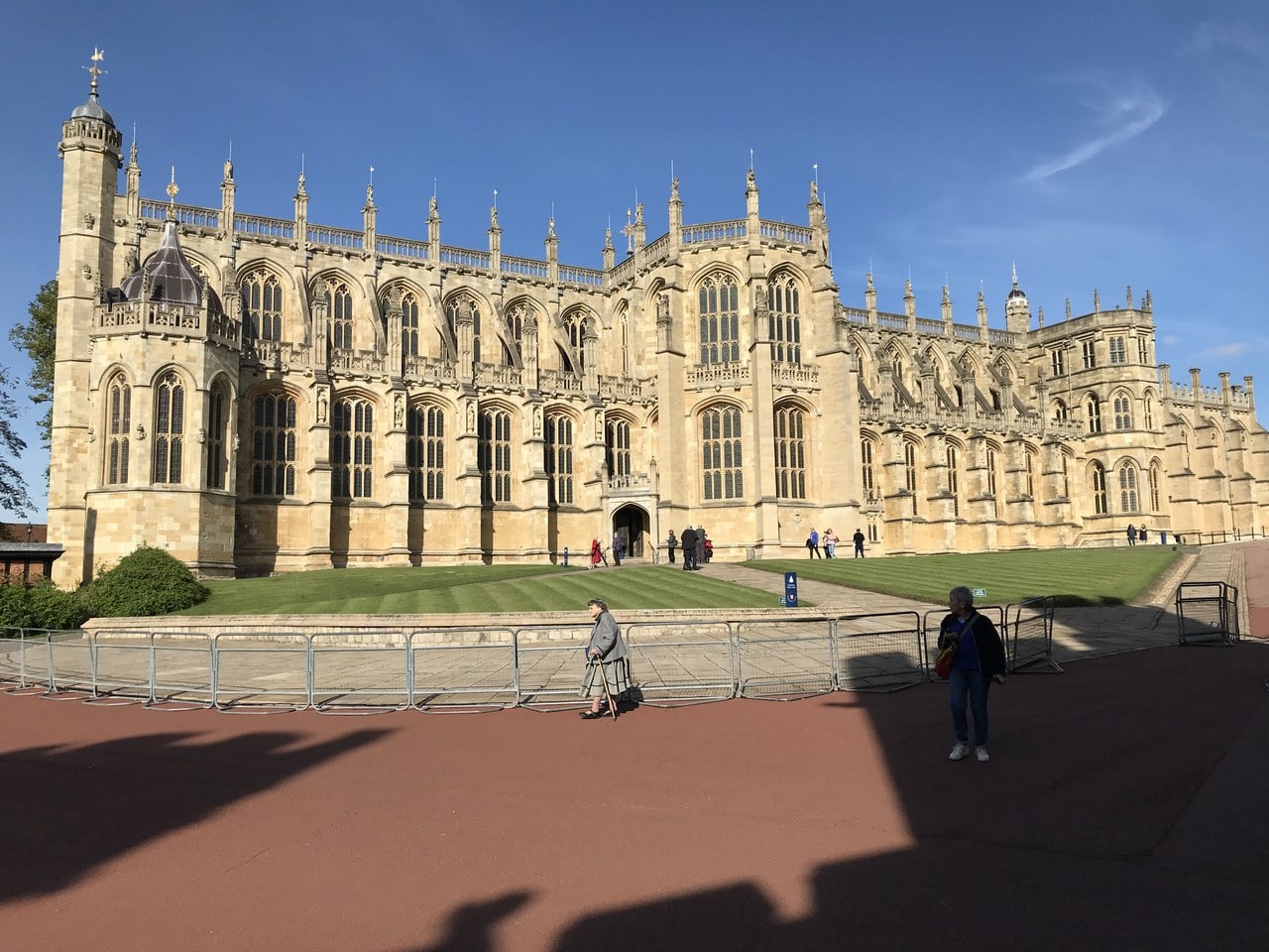 A long Gothic chapel of pale stone with large traceried windows, flying buttresses and pinnacles, seen across an open forecourt A long Gothic chapel of pale stone with large traceried windows, flying buttresses and pinnacles, seen across an open forecourt
