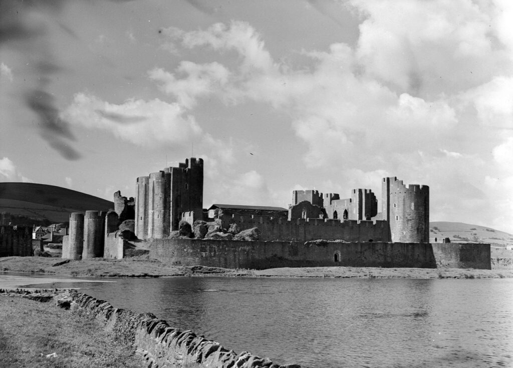 Caerphilly Castle 11 A black-and-white photograph of Caerphilly Castle's gatehouses and walls across a stretch of water, with hills behind