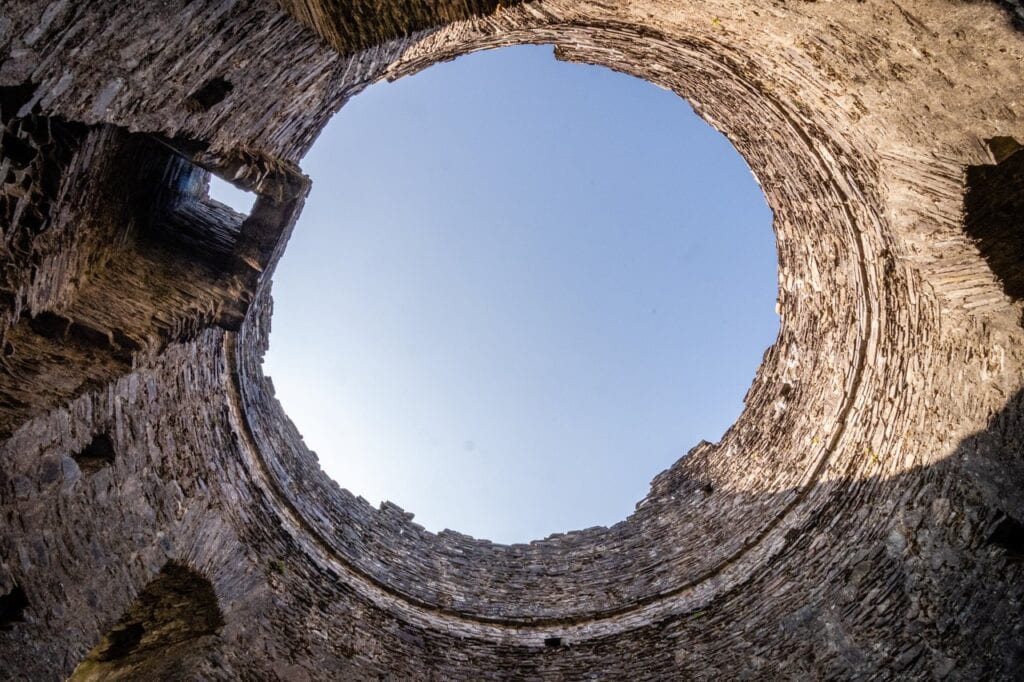Dolbadarn Castle 8 Looking straight up inside a roofless round stone tower to a circle of blue sky, with a window opening in the wall near the rim